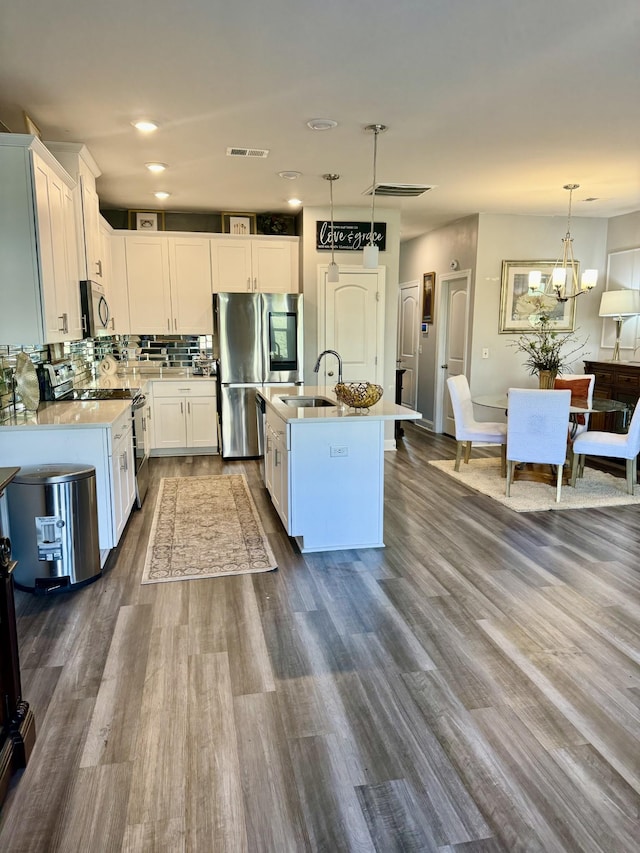 kitchen featuring white cabinetry, an island with sink, appliances with stainless steel finishes, and pendant lighting