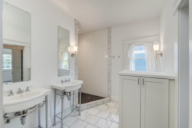 bathroom with double sink and tiled shower