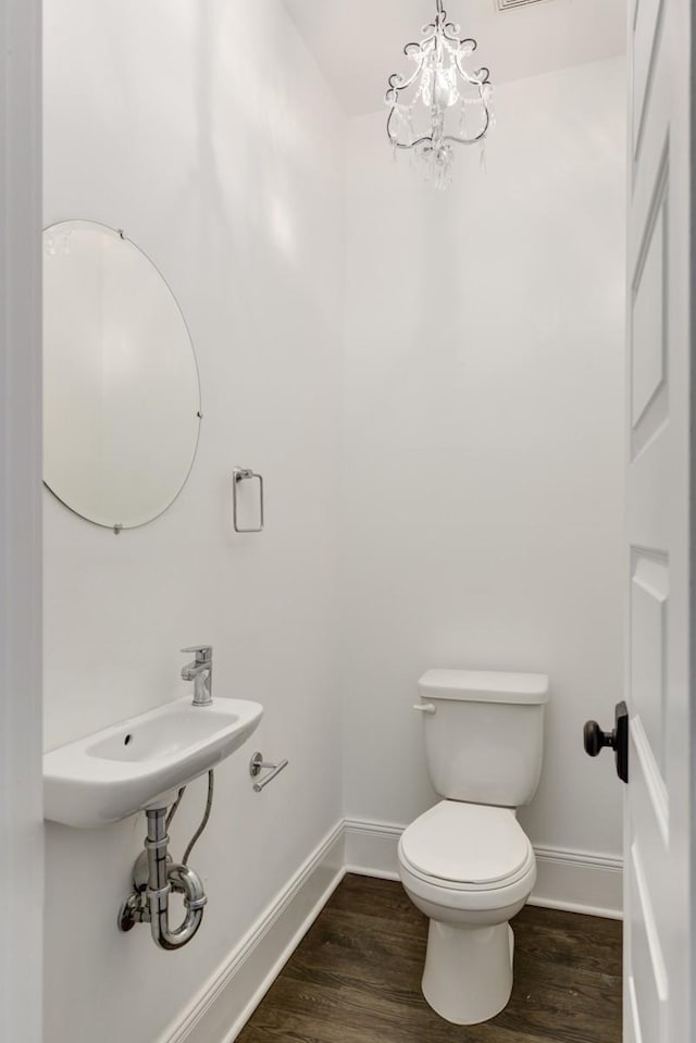 bathroom with hardwood / wood-style flooring, a chandelier, and toilet