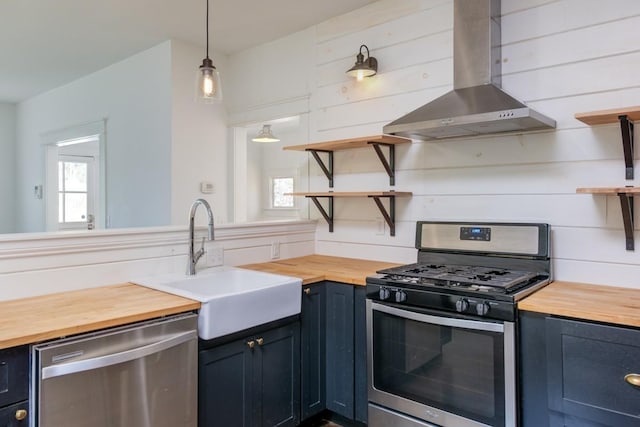 kitchen featuring sink, extractor fan, wooden counters, pendant lighting, and stainless steel appliances