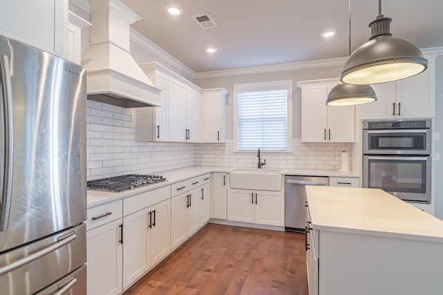 kitchen featuring white cabinets, appliances with stainless steel finishes, custom range hood, and backsplash