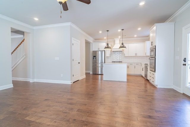 kitchen featuring pendant lighting, stainless steel appliances, a center island, tasteful backsplash, and white cabinets