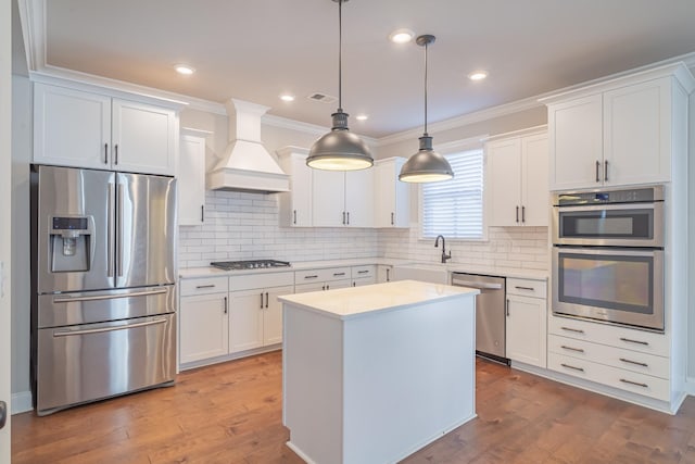 kitchen with white cabinetry, decorative light fixtures, custom exhaust hood, and appliances with stainless steel finishes