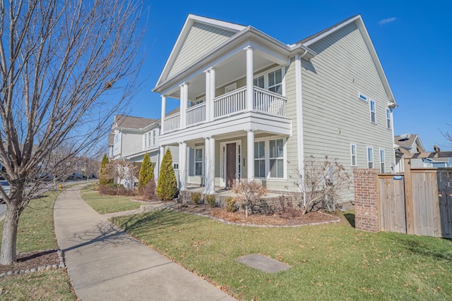 view of front of property featuring a balcony, covered porch, and a front lawn