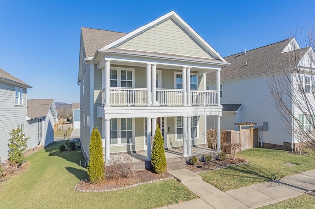 view of front of home with a balcony, covered porch, and a front lawn