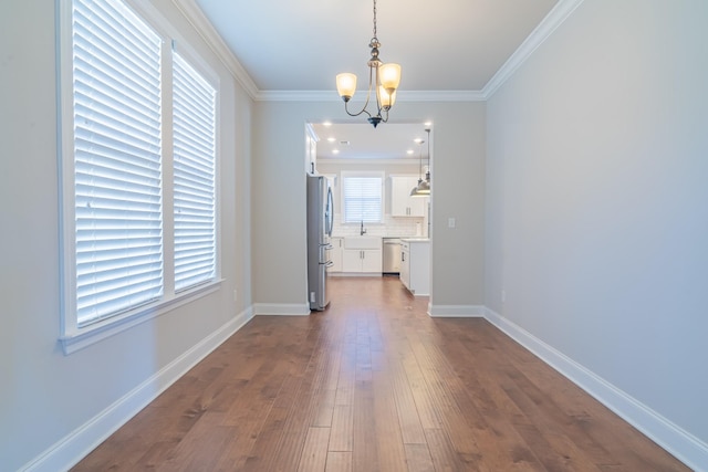 unfurnished dining area featuring ornamental molding, dark hardwood / wood-style floors, a chandelier, and sink