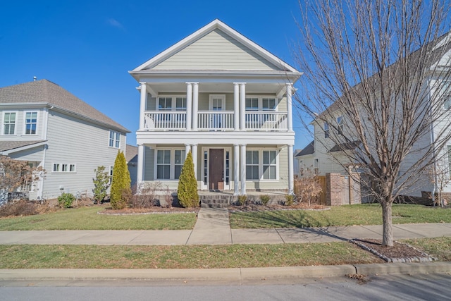 greek revival inspired property featuring a balcony and a front yard