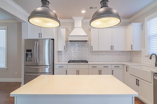 kitchen featuring backsplash, custom range hood, white cabinets, and appliances with stainless steel finishes