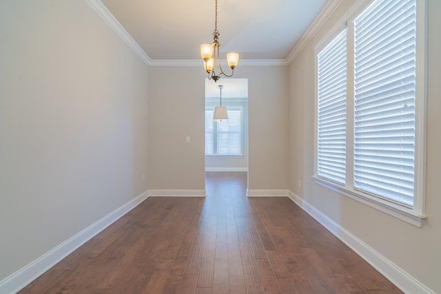 spare room featuring ornamental molding, dark wood-type flooring, and a chandelier