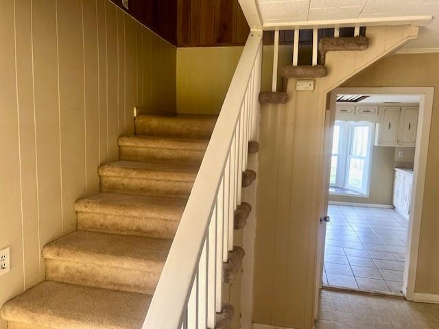 staircase featuring ornamental molding and tile patterned floors