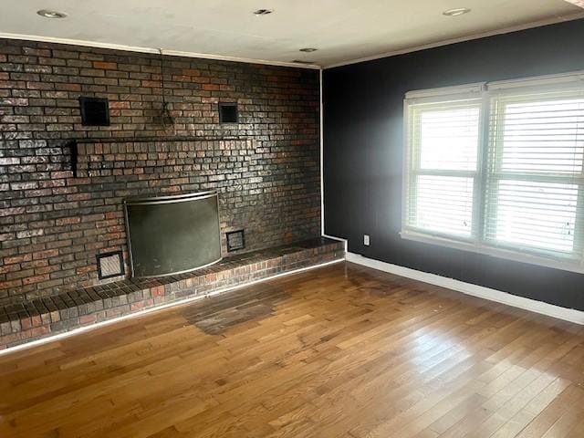 unfurnished living room with crown molding, a fireplace, and hardwood / wood-style floors