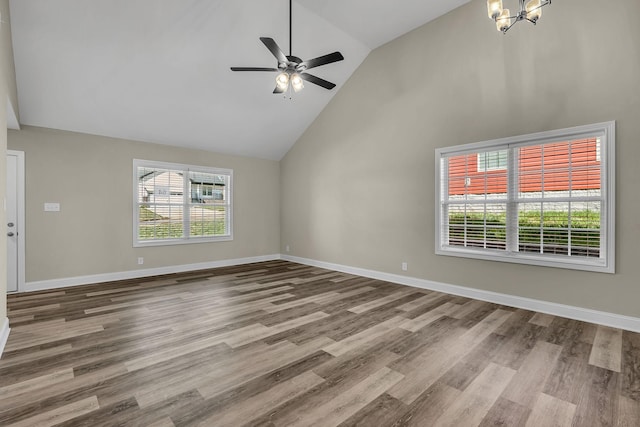 unfurnished living room with ceiling fan with notable chandelier, hardwood / wood-style floors, and high vaulted ceiling