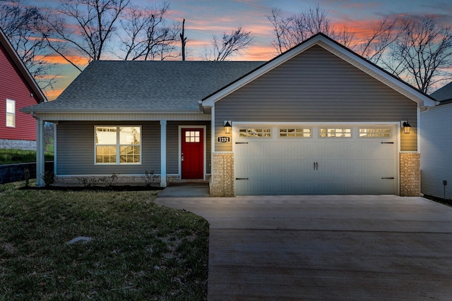 view of front of property featuring a yard, a garage, and covered porch