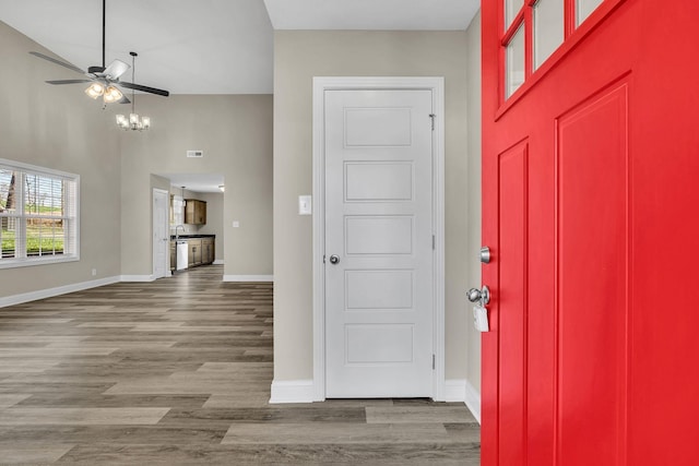 entryway with wood-type flooring, a chandelier, and a high ceiling