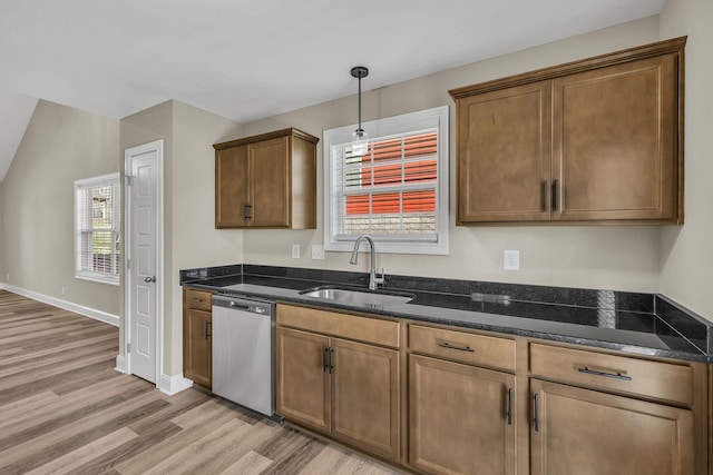 kitchen featuring decorative light fixtures, dishwasher, sink, dark stone countertops, and light wood-type flooring