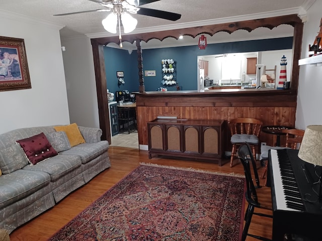 living room with hardwood / wood-style flooring, ceiling fan, ornamental molding, and a textured ceiling