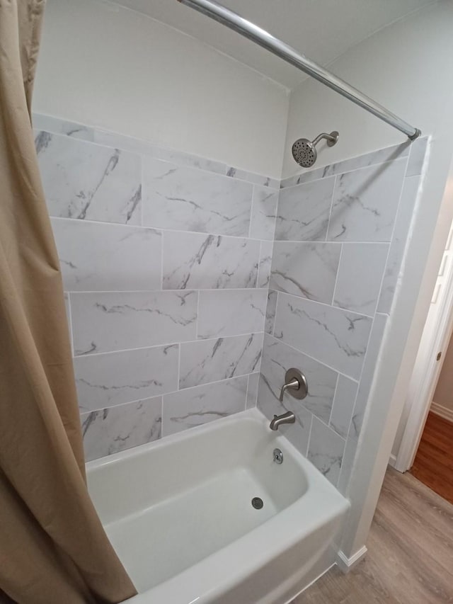 bathroom featuring hardwood / wood-style flooring and shower / bathtub combination with curtain