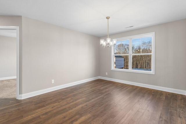 spare room with dark wood-type flooring and a chandelier