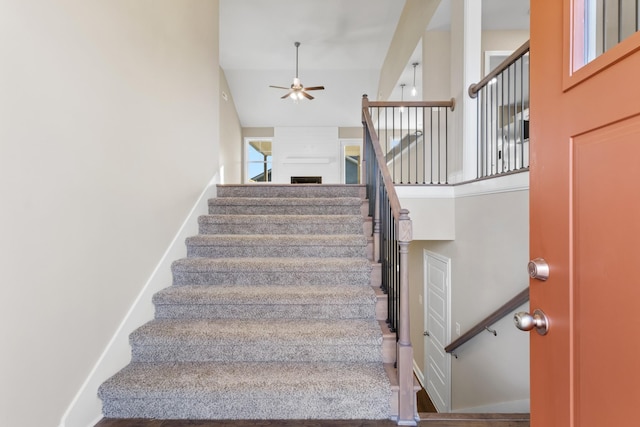 staircase with ceiling fan and a towering ceiling