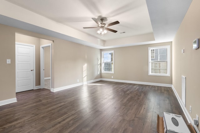 spare room featuring dark hardwood / wood-style floors, ceiling fan, and a tray ceiling