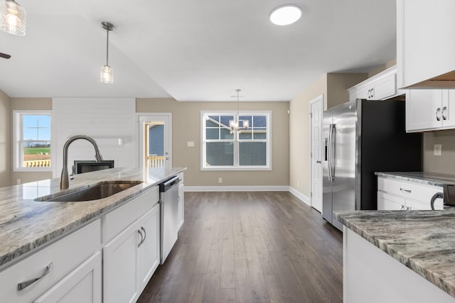 kitchen with light stone countertops, sink, white cabinets, and decorative light fixtures