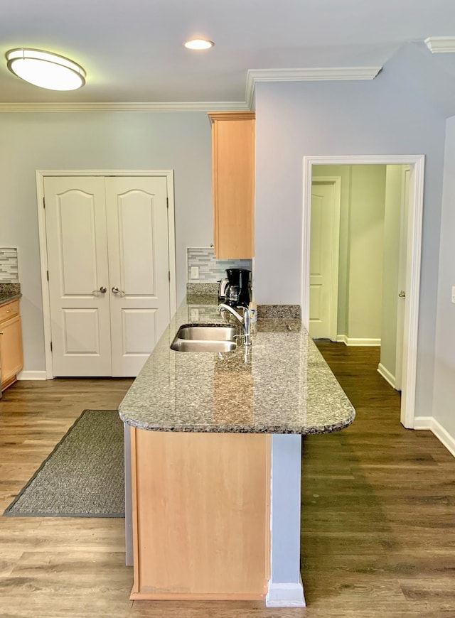 kitchen with stone counters, crown molding, light brown cabinets, and kitchen peninsula