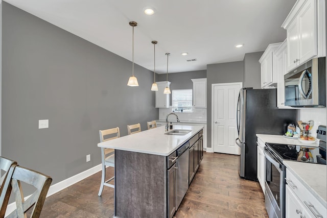 kitchen with an island with sink, sink, white cabinets, a kitchen bar, and stainless steel appliances