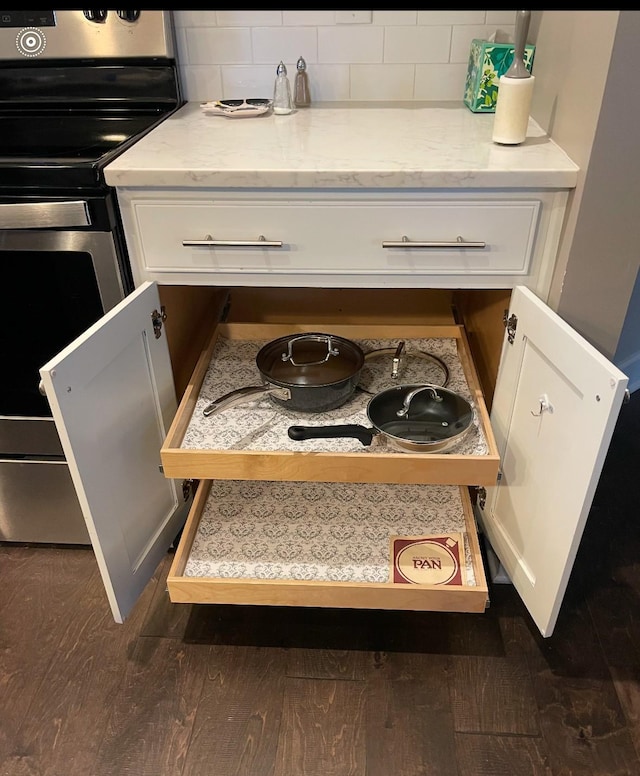 interior details featuring tasteful backsplash, dark hardwood / wood-style flooring, stainless steel range with electric cooktop, and white cabinets