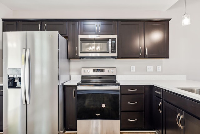 kitchen featuring hanging light fixtures, dark brown cabinets, and stainless steel appliances