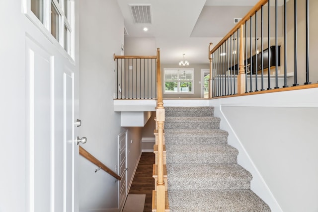 stairs featuring wood-type flooring and a notable chandelier