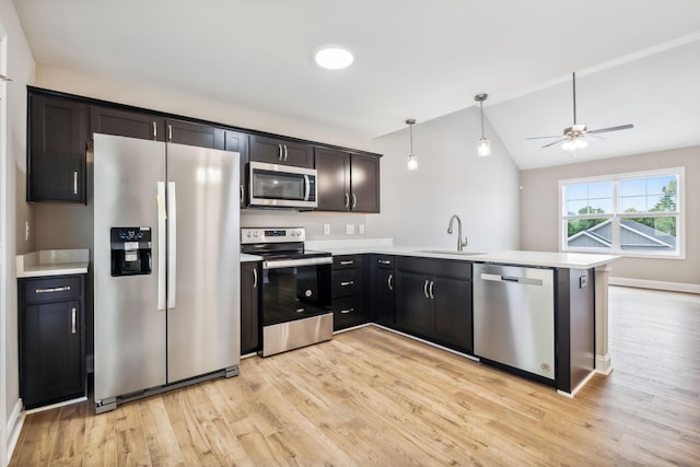 kitchen with sink, stainless steel appliances, decorative light fixtures, kitchen peninsula, and light wood-type flooring