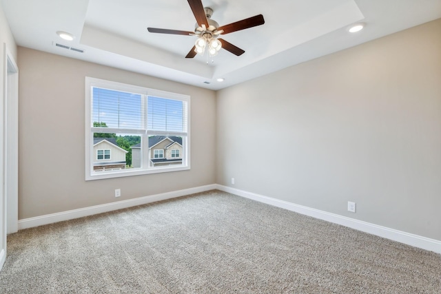 empty room featuring carpet, ceiling fan, and a tray ceiling