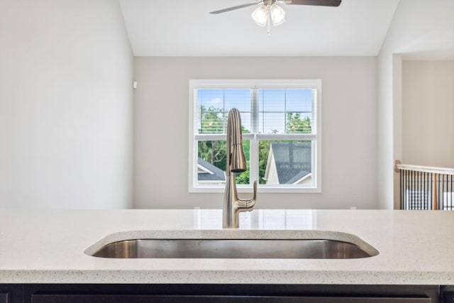 kitchen with sink, vaulted ceiling, light stone countertops, and ceiling fan