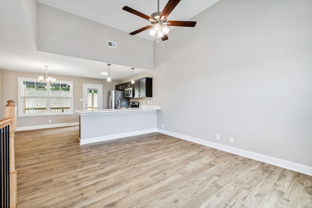 kitchen with ceiling fan with notable chandelier, wood-type flooring, kitchen peninsula, and appliances with stainless steel finishes