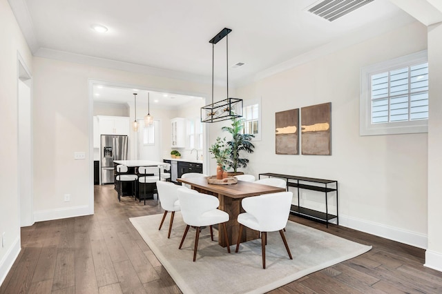 dining space featuring ornamental molding, sink, and dark hardwood / wood-style flooring