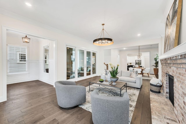 living room with wood-type flooring, a chandelier, and a brick fireplace