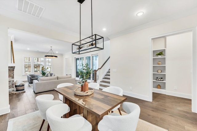 dining area with ornamental molding, a fireplace, and light hardwood / wood-style flooring