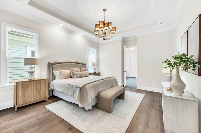 bedroom with an inviting chandelier, dark hardwood / wood-style flooring, and a tray ceiling