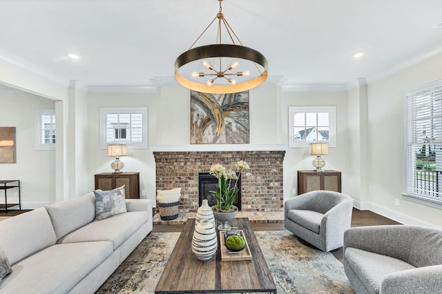 living room with hardwood / wood-style flooring, ornamental molding, a fireplace, and a chandelier