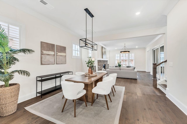 dining room with a fireplace, crown molding, and dark wood-type flooring