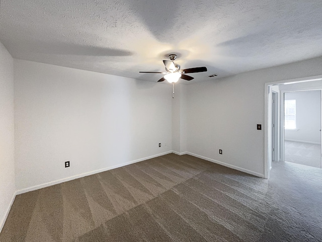 spare room with dark colored carpet, ceiling fan, and a textured ceiling