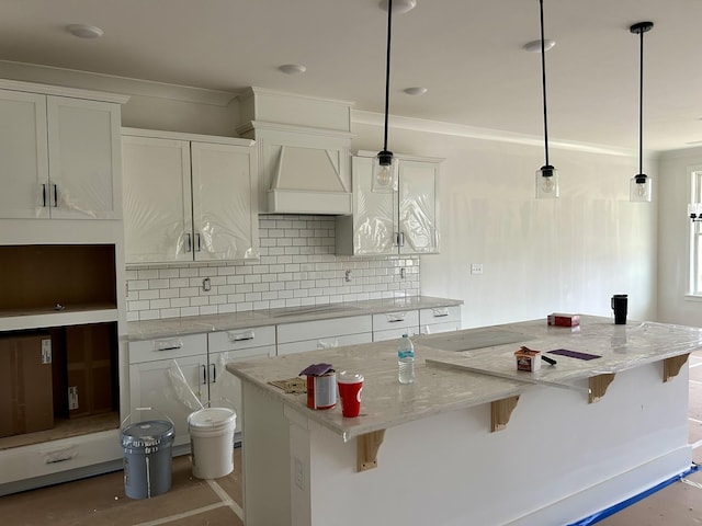 kitchen featuring pendant lighting, a kitchen island, custom range hood, and white cabinets