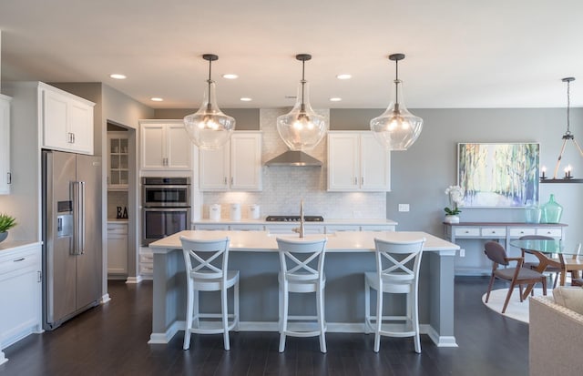 kitchen featuring a center island with sink, white cabinetry, appliances with stainless steel finishes, and pendant lighting