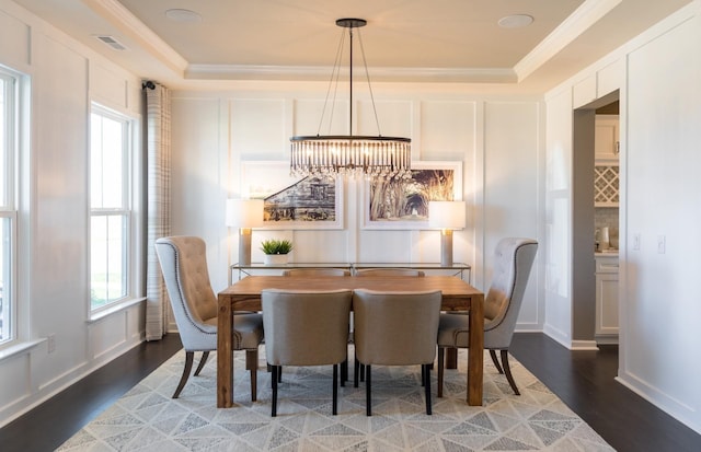 dining area featuring a tray ceiling, wood-type flooring, and ornamental molding