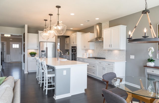 kitchen with white cabinetry, stainless steel appliances, and wall chimney range hood