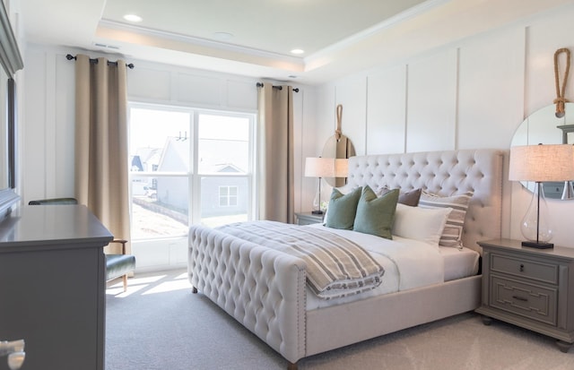 bedroom featuring crown molding, a tray ceiling, and light carpet