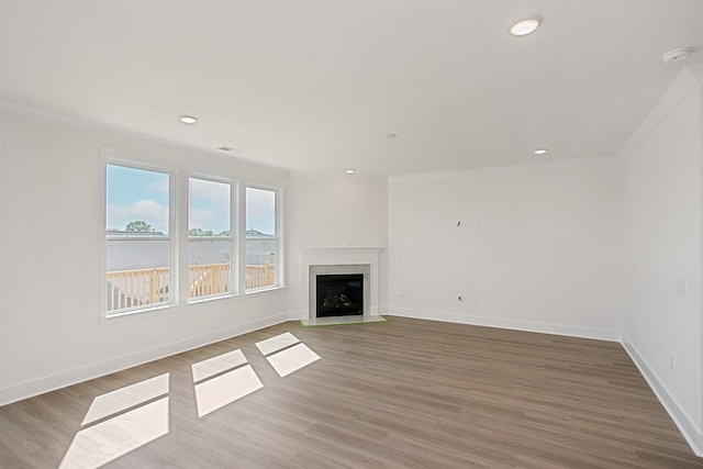 unfurnished living room with hardwood / wood-style floors, crown molding, and a premium fireplace