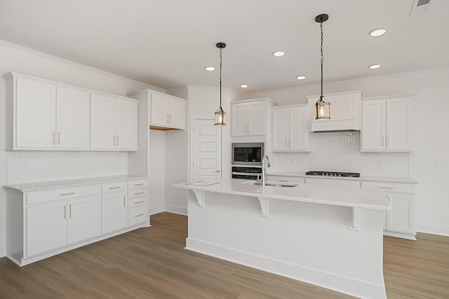 kitchen with sink, hardwood / wood-style floors, an island with sink, and white cabinets