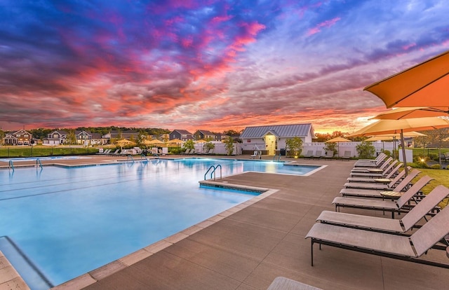 pool at dusk featuring a patio area