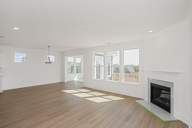 unfurnished living room featuring a wealth of natural light, a fireplace, ornamental molding, and wood-type flooring